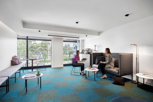 two women sitting in a room with tables and chairs at Quest Burwood East in Burwood