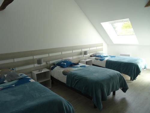 LA COURTEILLE في Saint-Fraimbault-sur-Pisse: غرفة نوم بسريرين مع شراشف زرقاء ونافذة