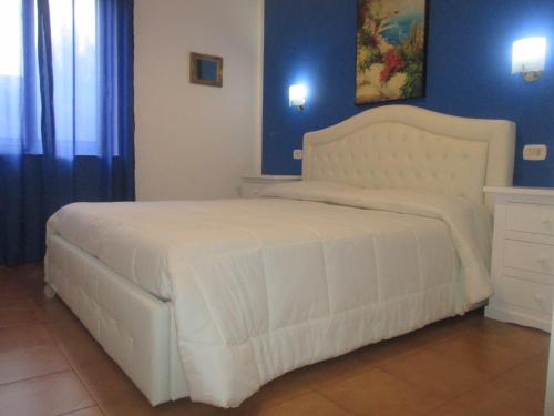 een wit bed in een slaapkamer met blauwe muren bij Palinuro casa vacanze "Donna Antonia" in Palinuro