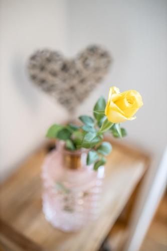 a vase with a yellow rose and a heart at Kärnten Apartment Turnersee in Sankt Kanzian