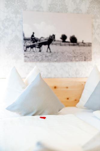 a bed with white pillows and a picture of a horse drawn carriage at Kärnten Apartment Turnersee in Sankt Kanzian