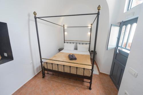 a bedroom with a bed with a black frame at Lotza Studios in Oia