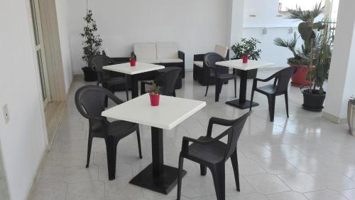 un restaurante con mesas blancas y sillas negras en Kali Nitta Salento en Sant'Isidoro