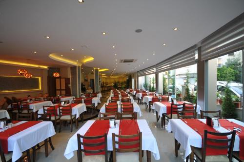 a restaurant with red and white tables and chairs at Kleopatra Micador Otel in Alanya