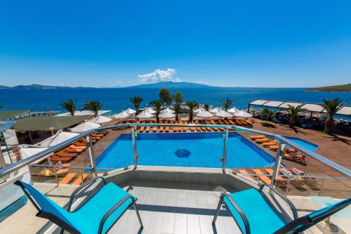 a resort swimming pool with lounge chairs and the ocean at Hotel Saranda Palace in Sarandë