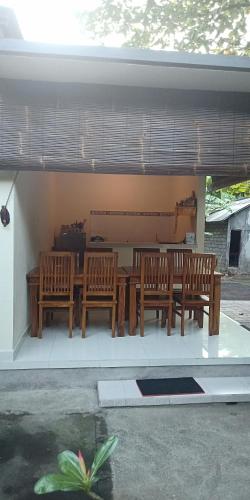 a patio with wooden benches and a table and chairs at Pondok Aldi in Amed