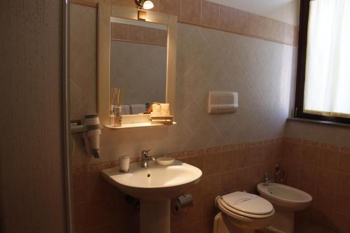 La salle de bains est pourvue d'un lavabo, de toilettes et d'un miroir. dans l'établissement Residence Hotel La Commenda, à Montefiascone