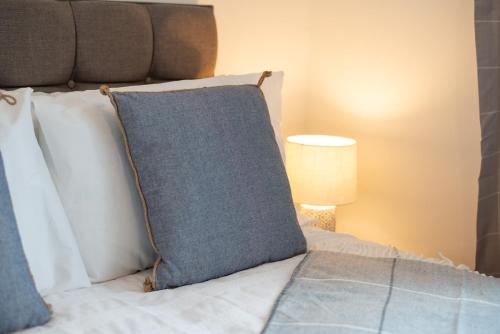 a bed with a blue pillow on it with a lamp at Contractor-Approved - 4 Bed - Smart TVs - Access M4 in Swansea
