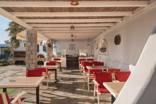a restaurant with red chairs and tables on a patio at Alexandros Village in Adamas