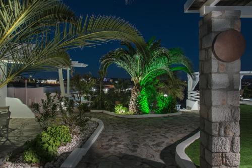 a garden with palm trees and lights at night at Alexandros Village in Adamas