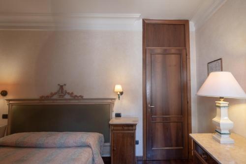 a bedroom with a bed and a lamp and a door at Relais Ducale in Gubbio