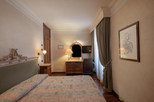 a bedroom with a bed and a dresser and a mirror at Relais Ducale in Gubbio