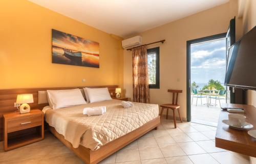 a bedroom with a bed and a tv and a balcony at Summer Sun in Skala
