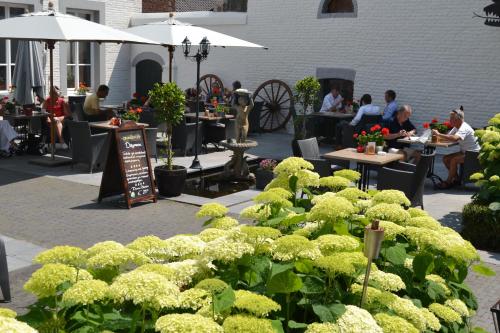 a garden area with tables, chairs and umbrellas at Hotel Kasteel Doenrade in Doenrade