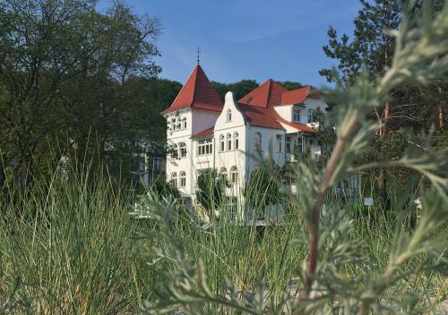 een groot wit gebouw met een rood dak bij Hotel Pension Haus Colmsee in Binz