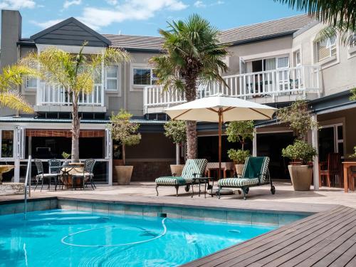 a swimming pool with patio furniture and an umbrella at Cinnamon Boutique Guest House in Wilderness