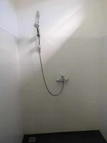 a shower with a hose attached to a white tile wall at Dream Estate Resort in Senggigi 