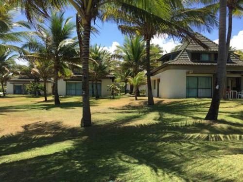 a house with palm trees in front of it at Beach Class Resort 2 quartos Muro Alto BMS in Porto De Galinhas