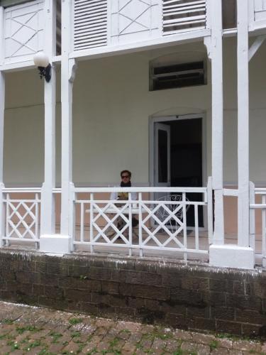 a man standing on the porch of a white house at BRIGHTLANDS HOTEL in Murree