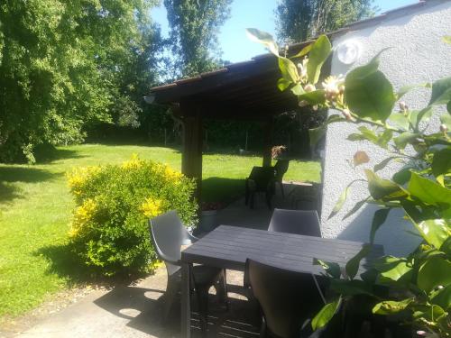 a patio with a table and chairs in a yard at Studio avec jardin à 5 min du Parc Walibi in Roquefort