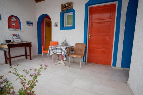 Habitación con mesa, sillas y puerta roja en Studios Zafiri en Naxos