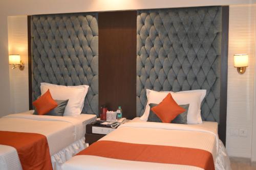 two beds in a hotel room with orange pillows at Southern Plaza in Kolkata