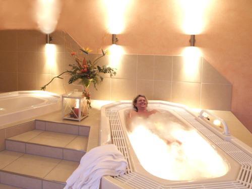 a woman laying in a bath tub in a bathroom at Hotel Hesborner Kuckuck in Hallenberg