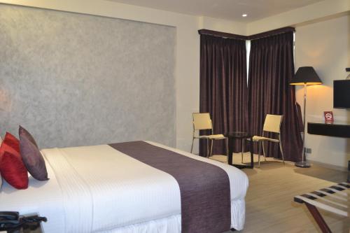 a hotel room with a bed and a table and chairs at Southern Plaza in Kolkata