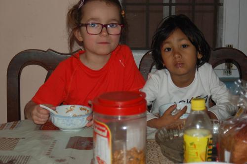 two young girls sitting at a table eating food at Shine Homestay Famille Francophone - Shine Home and Apartment in Kathmandu