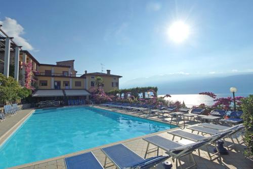 a large swimming pool with lounge chairs and the ocean at Hotel Palazzina in Gargnano