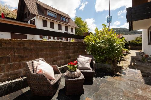 two chairs and a vase with flowers on a patio at Hotel Petra in Baiersbronn