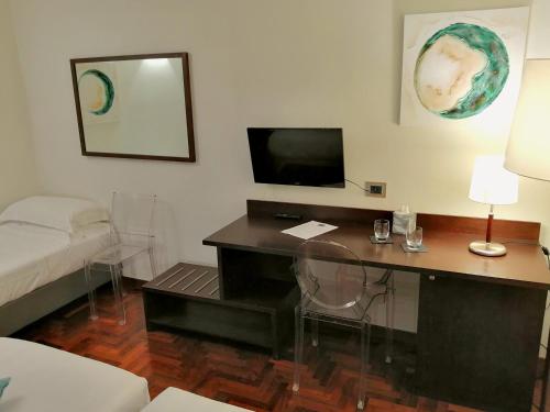 a room with a desk with a bed and a television at Locanda Giustini in Assisi