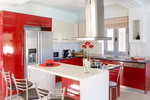 a kitchen with red and white cabinets and a white counter top at Thealos Village aparthotel Lefkada in Lygia