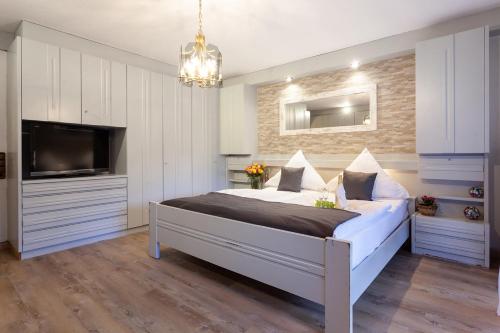 a bedroom with a large bed and a tv at Hotel Petra in Baiersbronn