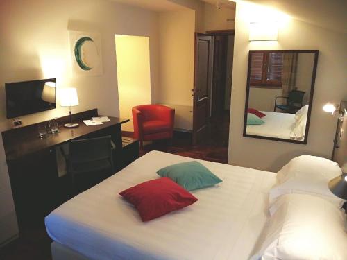 a hotel room with a bed and a desk and a mirror at Locanda Giustini in Assisi