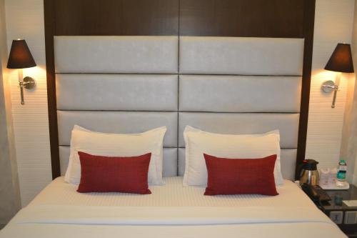 a bedroom with a large bed with two red pillows at Southern Plaza in Kolkata