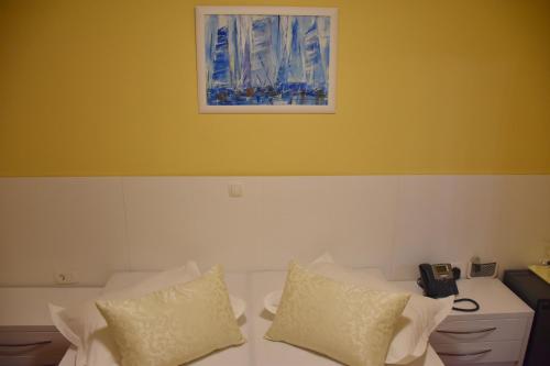 a bed with white pillows and a picture on the wall at Villa Riva in Makarska