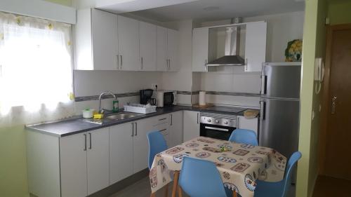 una cocina con mesa y sillas azules. en Apartamento en Avenida Quevedo, en León