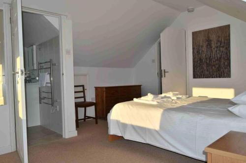 a bedroom with a white bed and a bathroom at Perran Steps in Perranporth