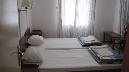 two twin beds in a room with a window at Tatsis Apartments in Masouri