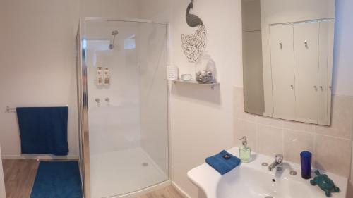 a white bathroom with a shower and a sink at Island Escape in Wimbledon Heights