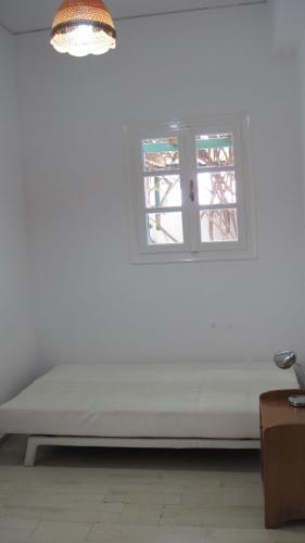a bed in a white room with a window at Tatsis Apartments in Masouri