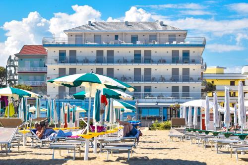 a beach with chairs and umbrellas and a building at Hotel Delle Nazioni in Caorle