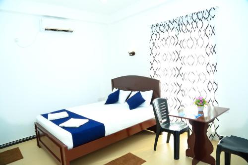 a bedroom with a bed and a table and a chair at Blue Diamond Resort in Trincomalee