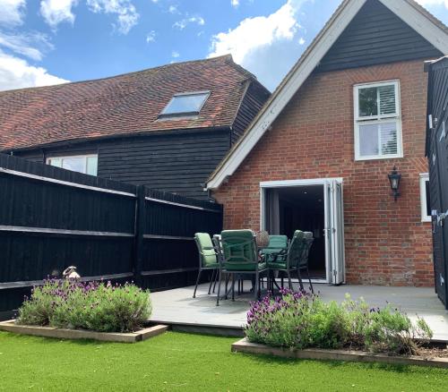 a patio with chairs and a table in front of a house at The Barn House in Cranleigh