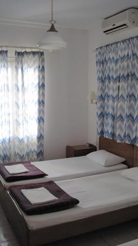 a bedroom with two beds with blue curtains at Tatsis Apartments in Masouri