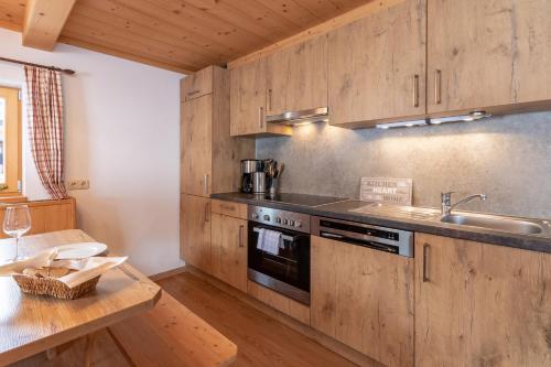 a kitchen with wooden cabinets and a sink and a stove at Berggasthof Staudachstub'n in Kirchberg in Tirol