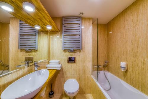 a bathroom with a tub and a toilet and a sink at Grand Częstochowa in Częstochowa