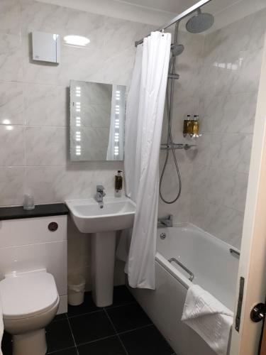 a bathroom with a sink and a toilet and a tub at Red Lion Hotel in Basingstoke