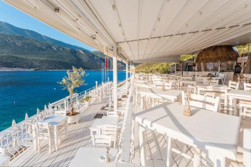 a restaurant with white tables and chairs overlooking the water at Club Çapa Hotel in Kas